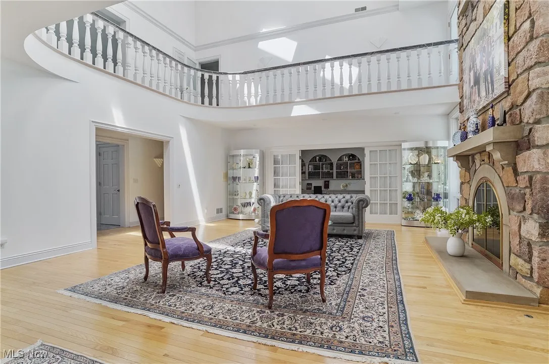 Living area with a stone fireplace, a high ceiling, and wood-type flooring