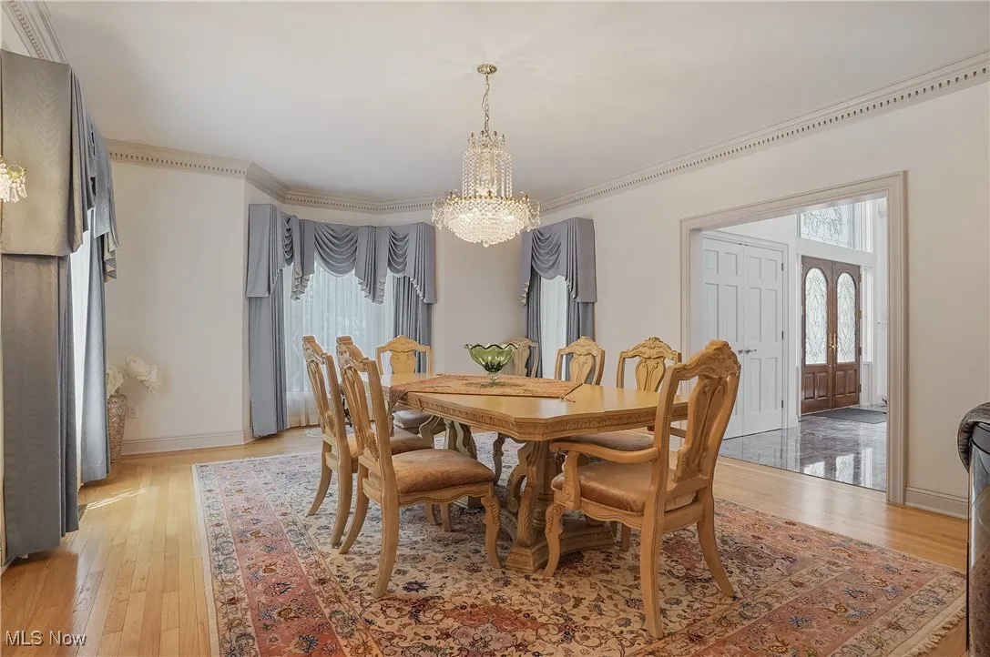 Dining area featuring a chandelier, light wood finished floors, plenty of natural light, and ornamental molding