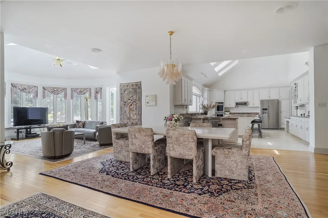 Dining room with light wood-style floors, a chandelier, a skylight, and high vaulted ceiling