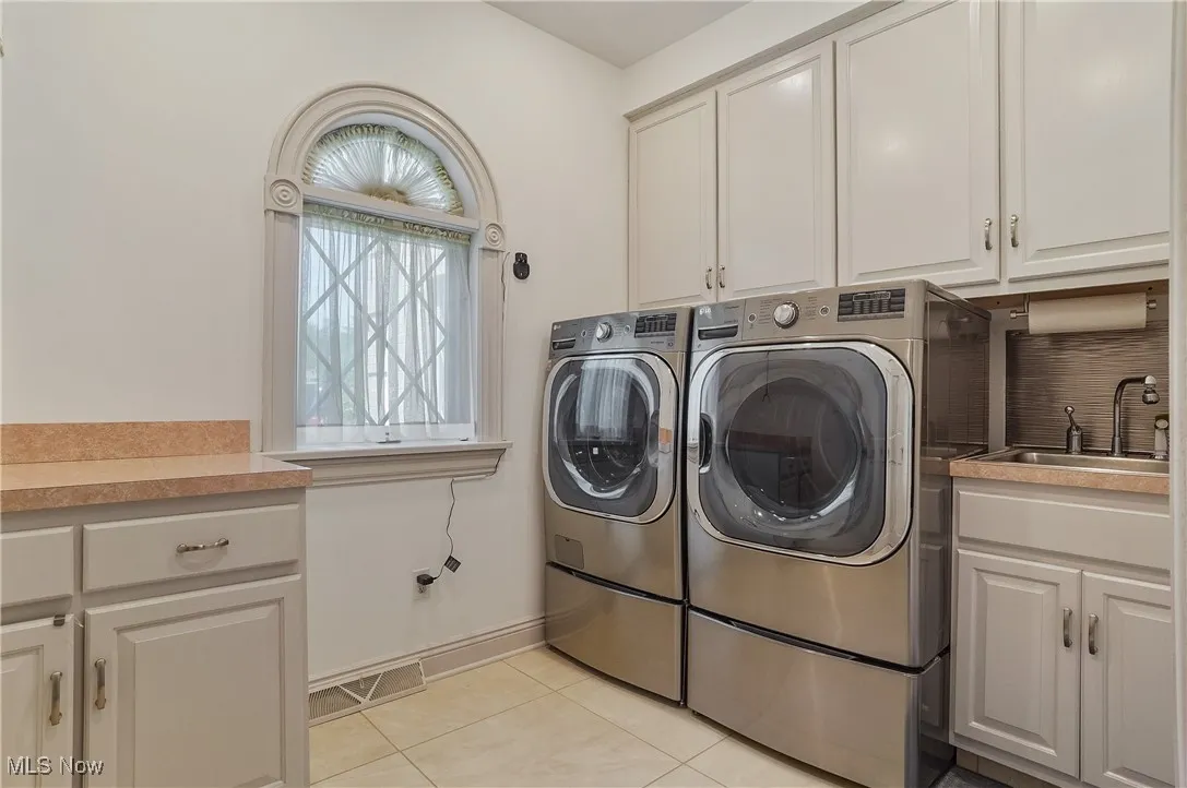 Laundry area featuring cabinet space, washer and clothes dryer, and light tile patterned floors