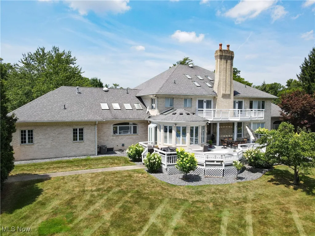 Back of house with roof with shingles, a chimney, a yard, and a deck