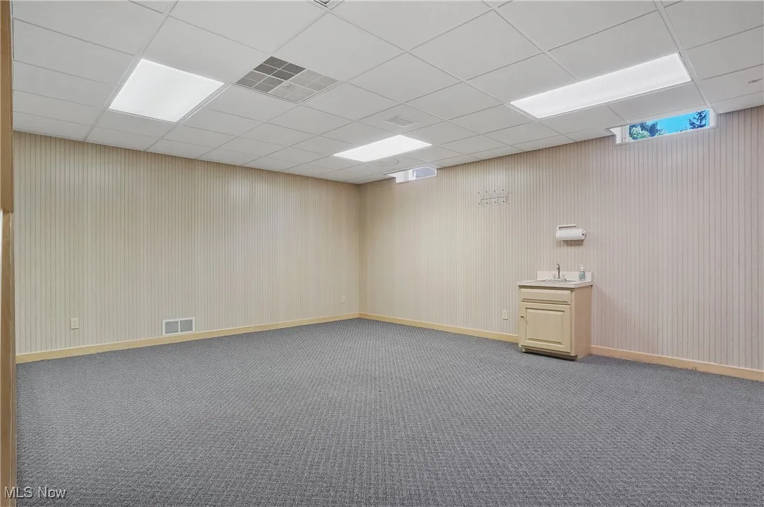Carpeted spare room with a paneled ceiling and baseboards