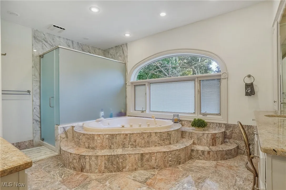 Bathroom with vanity, a stall shower, a whirlpool tub, recessed lighting, and marble finish floors