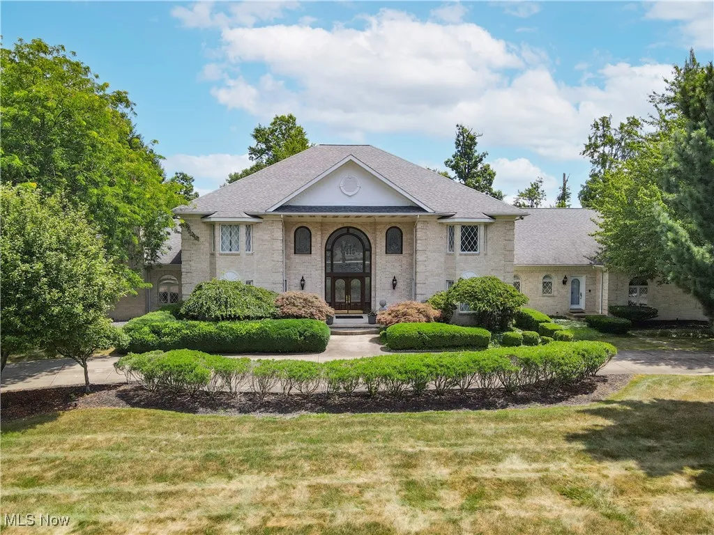 View of front of house with brick siding, a front lawn, roof with shingles, and french doors