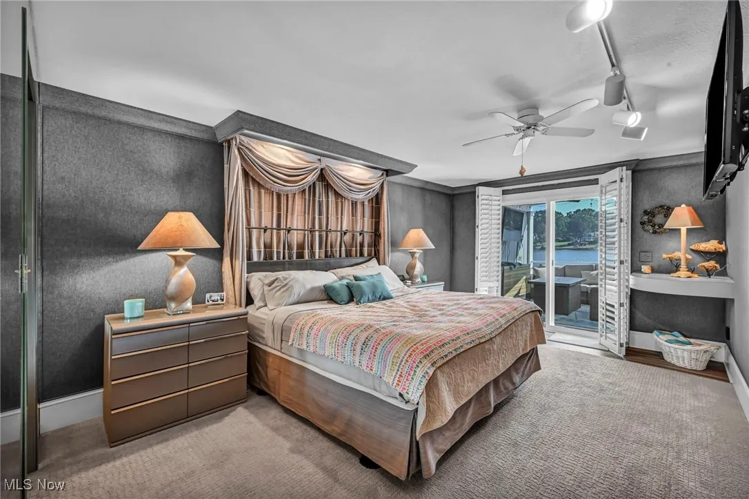 Bedroom with access to exterior, track lighting, carpet flooring, and a ceiling fan