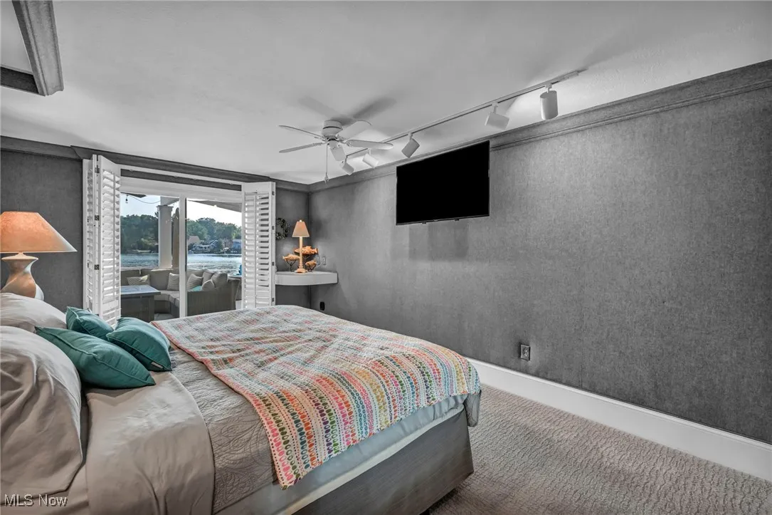 Carpeted bedroom with rail lighting, access to exterior, and a ceiling fan