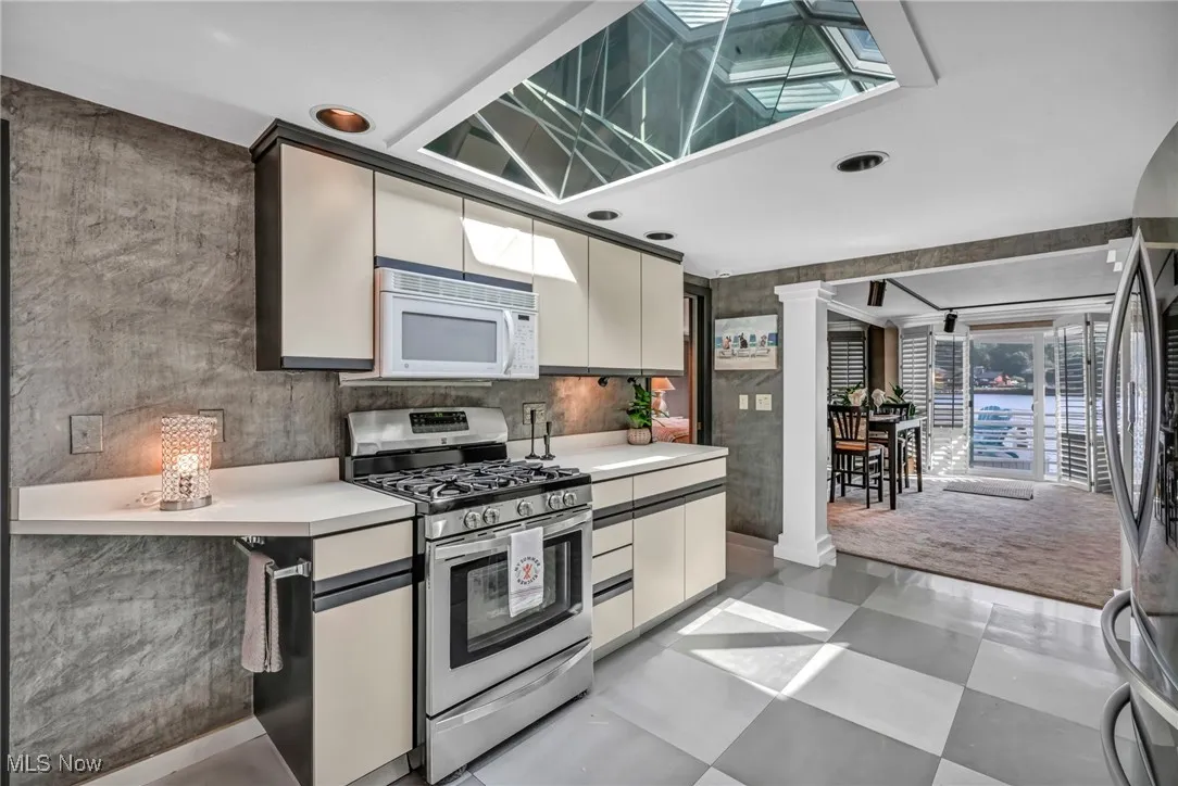 Kitchen featuring stainless steel appliances, light countertops, ornate columns, recessed lighting, and light floors
