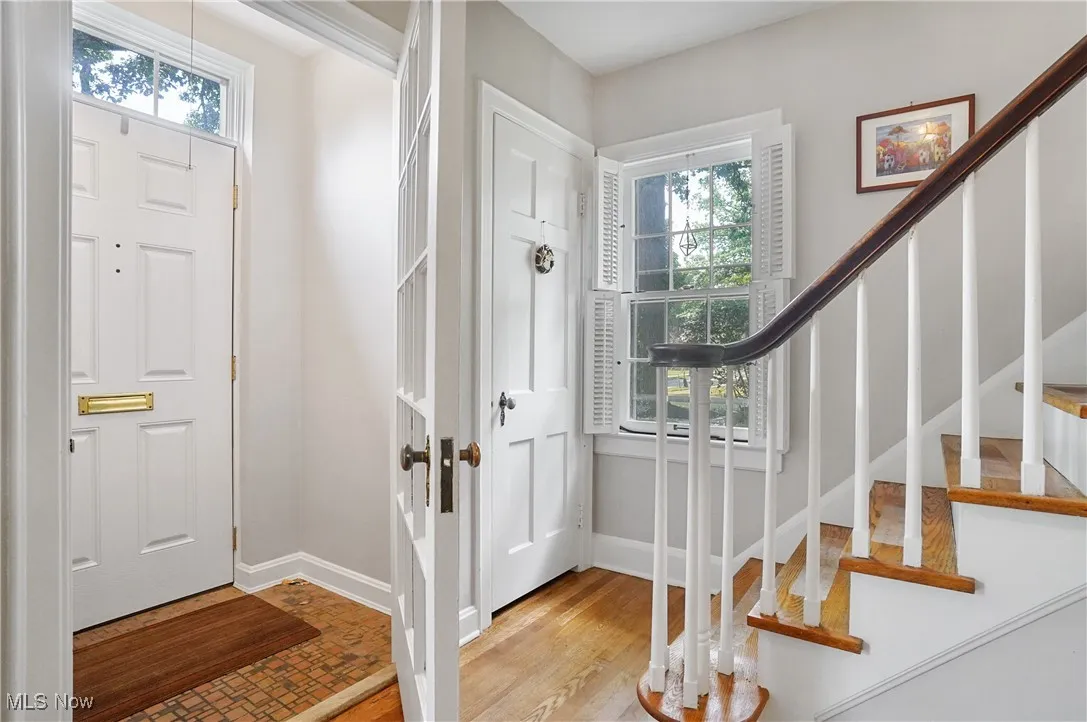 Foyer with healthy amount of natural light, stairway, and wood finished floors