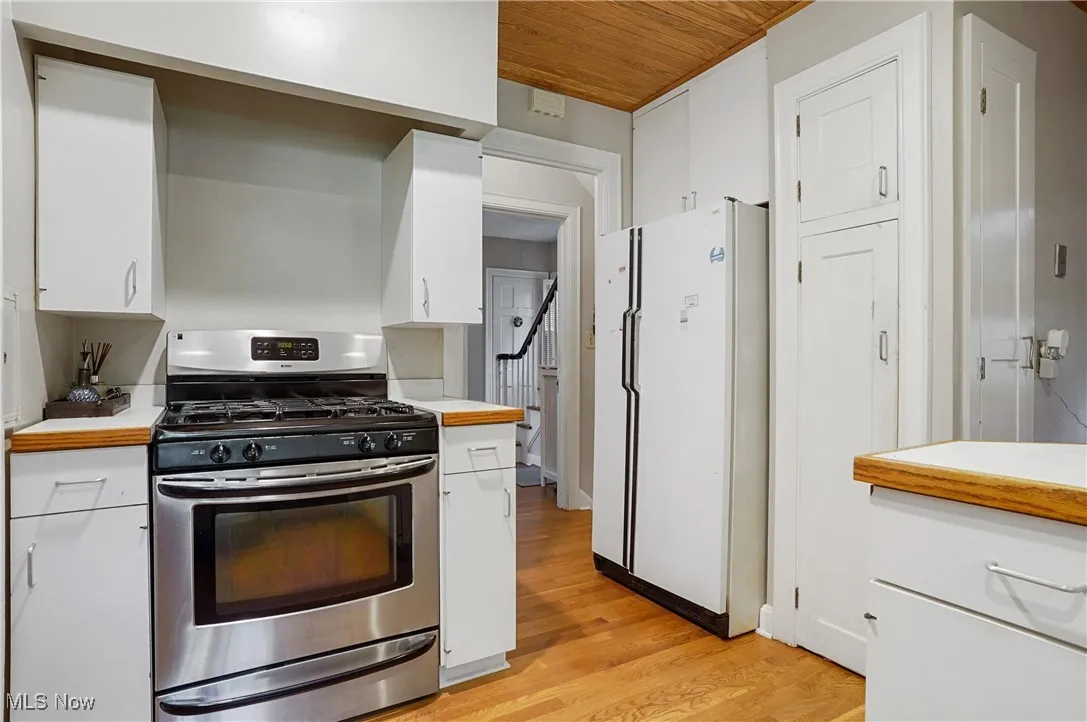 Kitchen featuring stainless steel gas range, freestanding refrigerator, light countertops, wooden ceiling, and light wood-type flooring