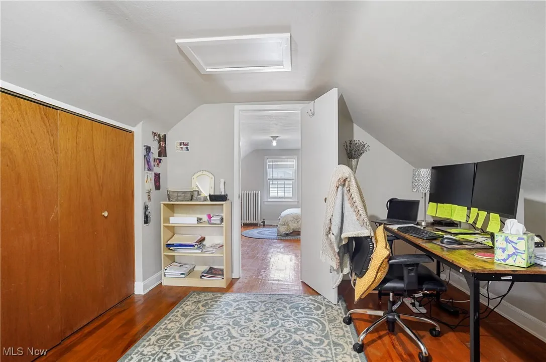 Office area featuring wood finished floors, lofted ceiling, and radiator heating unit