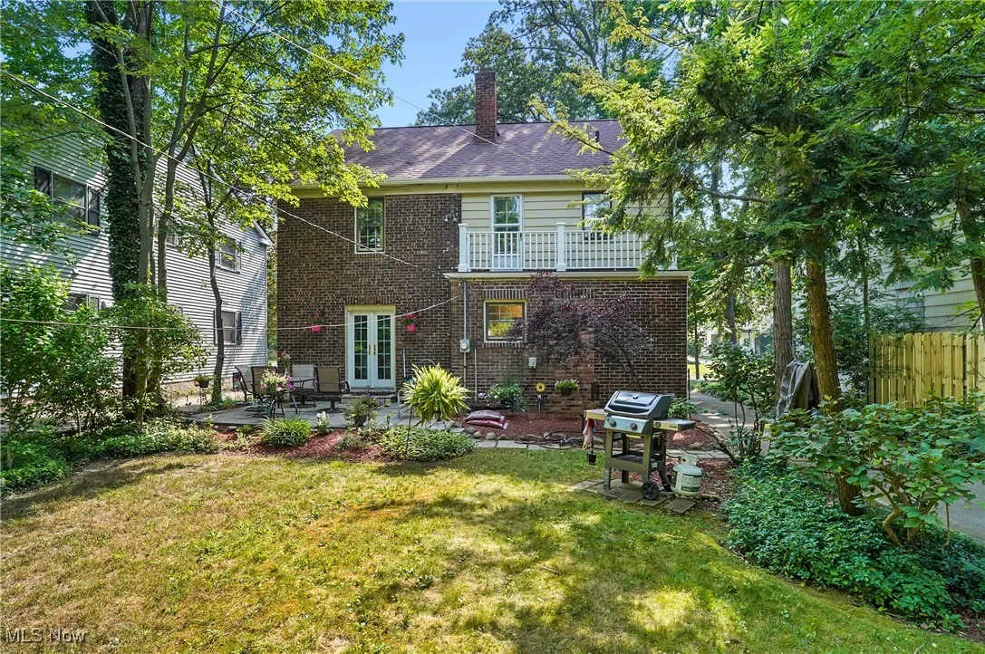 Back of property featuring a patio, a chimney, brick siding, a balcony, and french doors