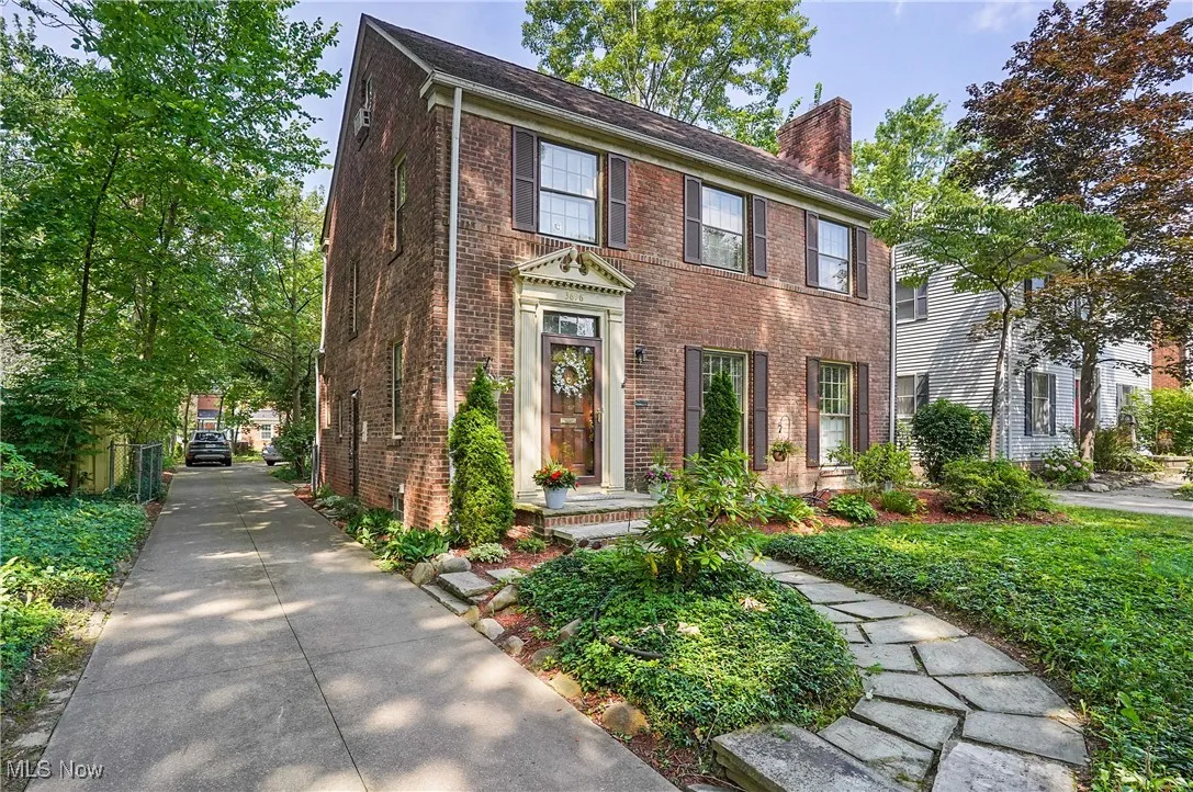 Colonial-style house with a chimney and brick siding