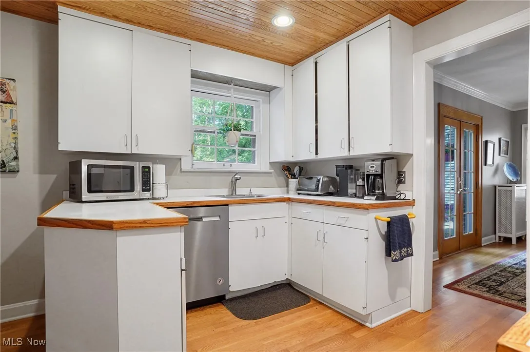 Kitchen featuring wood ceiling, light wood-style floors, appliances with stainless steel finishes, white cabinets, and light countertops