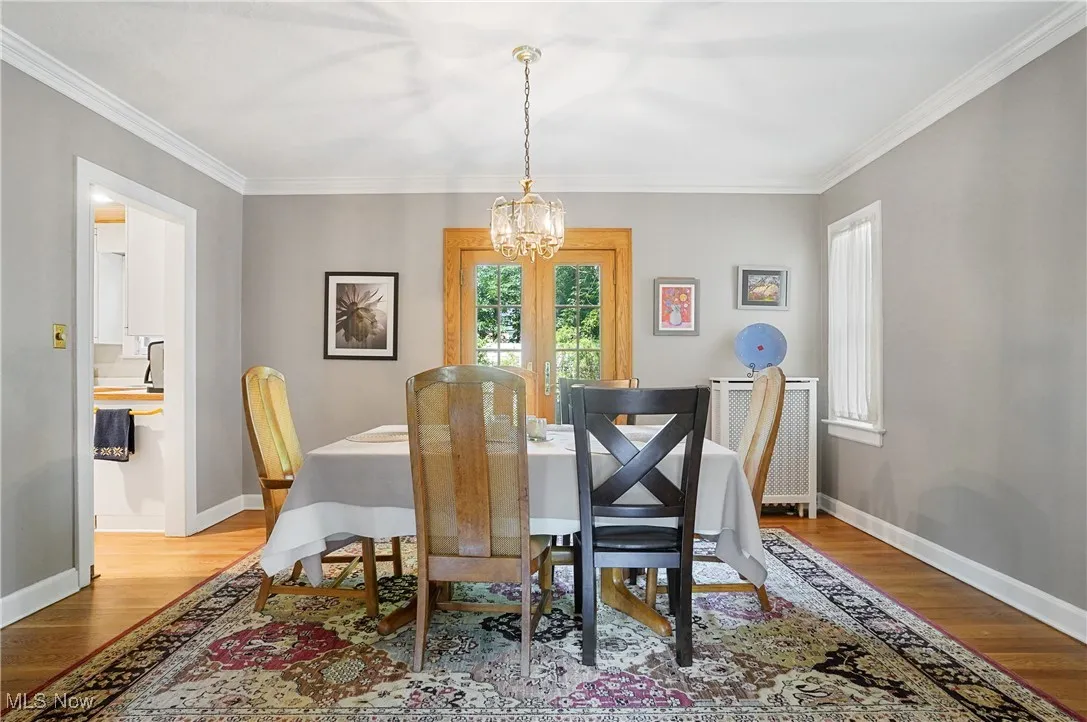 Dining room featuring a chandelier, wood finished floors, ornamental molding, and radiator heating unit