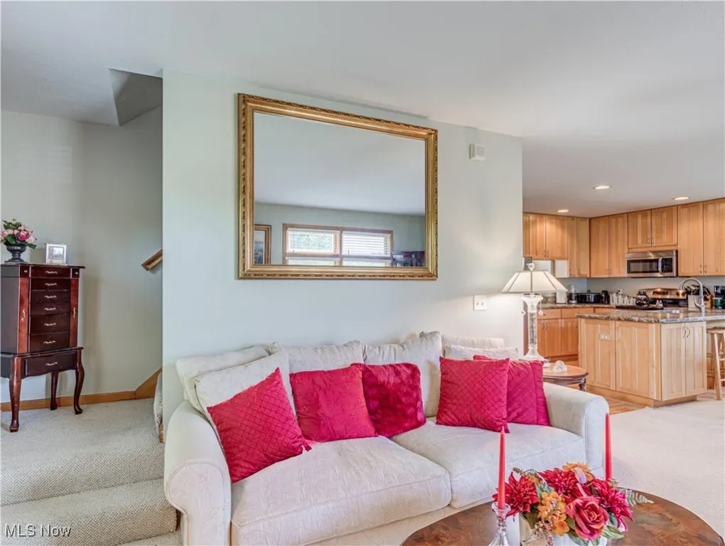 Living room is open to the Dining Room and the Kitchen.  The wall behind the sofa contains stairs leading to the second level on the left, and around the corner is a door with stairs leading to the finished basement