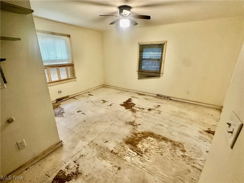 Unfurnished room featuring a ceiling fan and baseboards