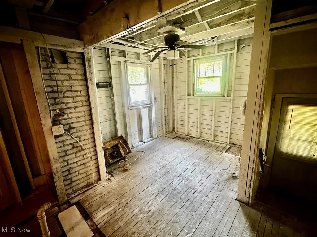 Unfurnished room featuring hardwood / wood-style flooring, a ceiling fan, and wooden walls