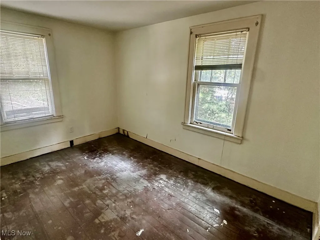 Unfurnished room with dark wood finished floors and baseboards