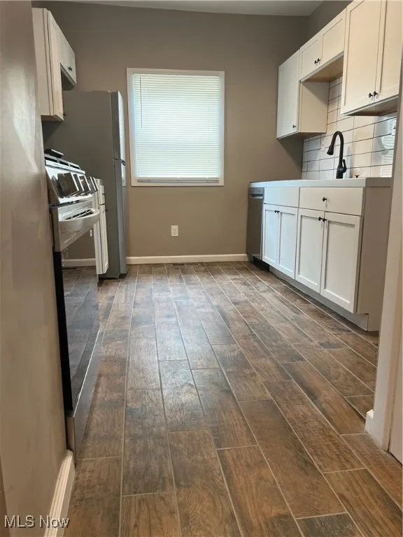 Kitchen featuring dark wood-style floors, tasteful backsplash, white cabinetry, and light countertops