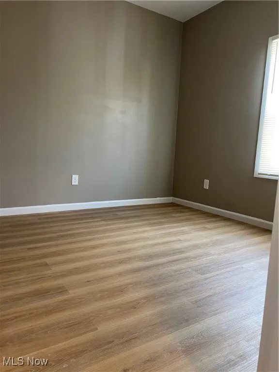 Unfurnished room with wood finished floors and baseboards