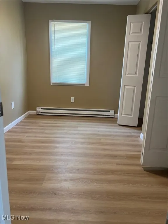 Empty room featuring light wood-type flooring and baseboard heating
