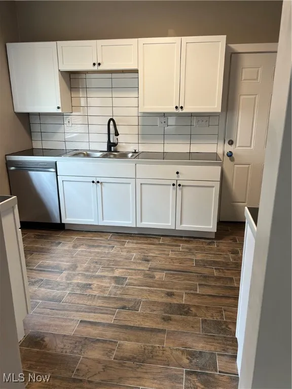 Kitchen featuring wood tiled floors, white cabinets, and backsplash