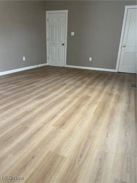 Spare room with baseboards and wood finished floors