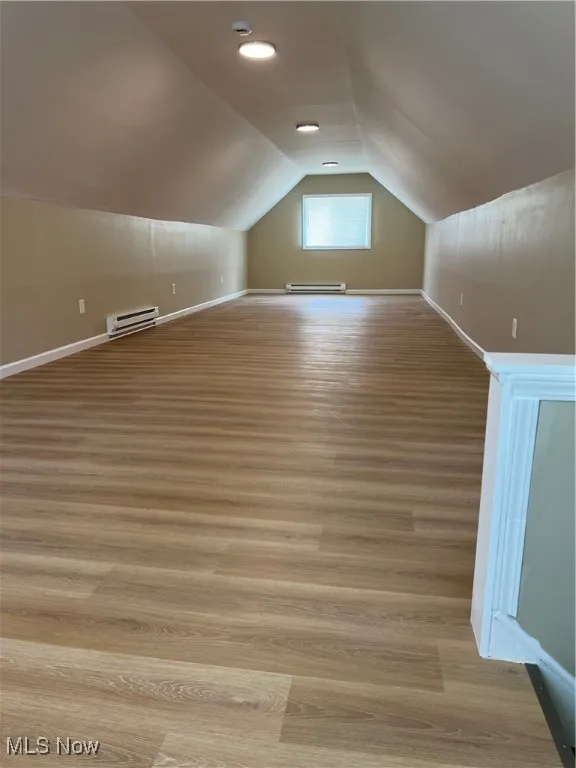 Bonus room featuring light wood finished floors, lofted ceiling, and a baseboard heating unit