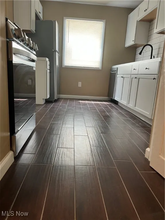 Kitchen featuring oven, white cabinets, decorative backsplash, dishwasher, and light countertops