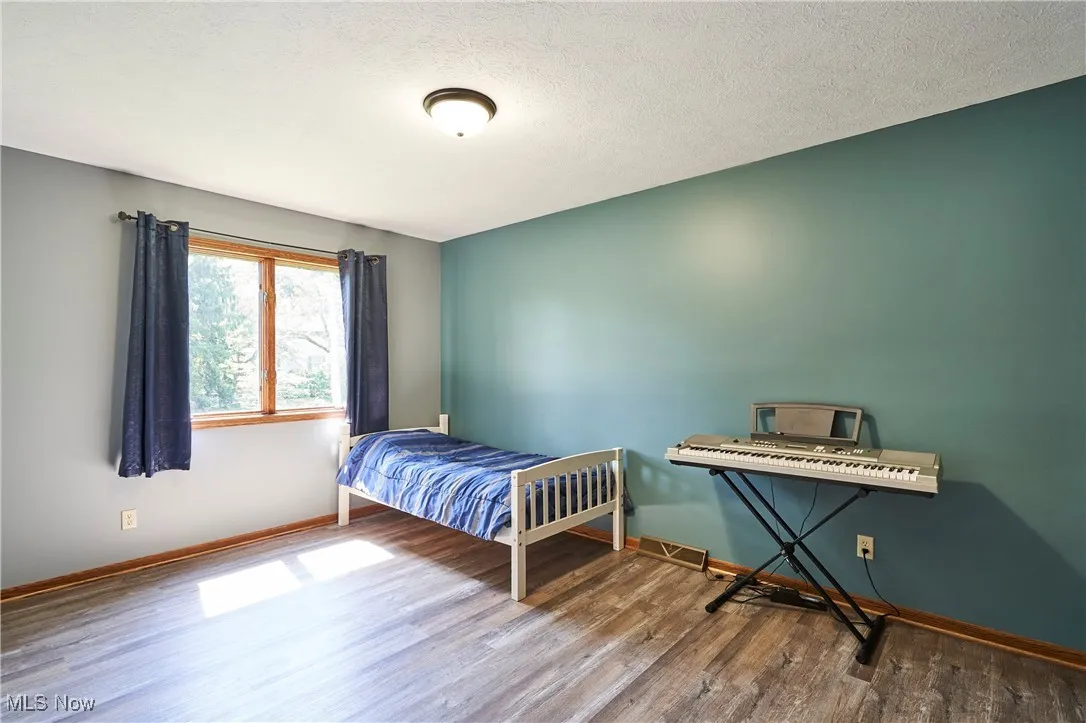 Bedroom with wood finished floors and a textured ceiling