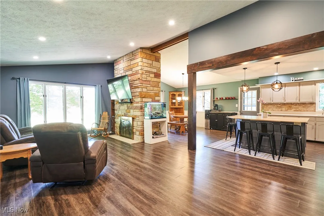 Living area featuring dark wood-type flooring, a textured ceiling, recessed lighting, and a fireplace
