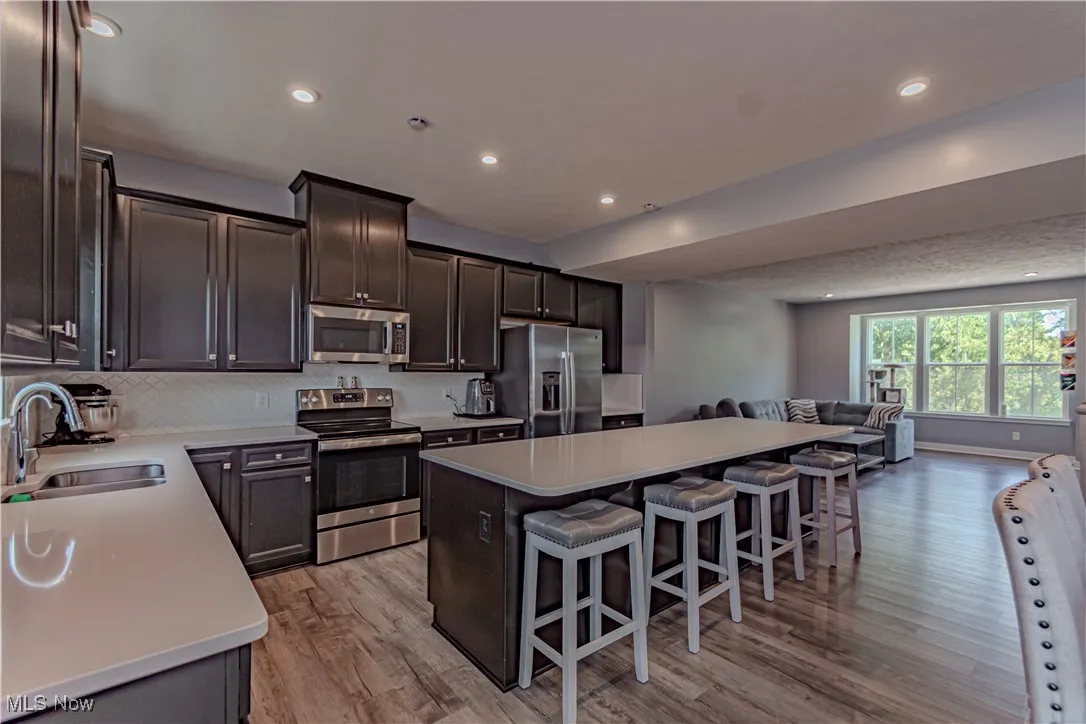 Kitchen with open floor plan, stainless steel appliances, a kitchen bar, recessed lighting, and light wood-style flooring