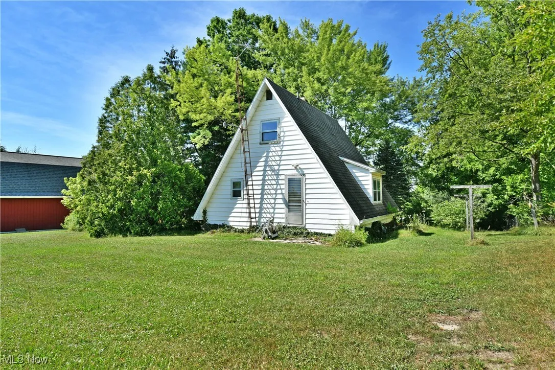 View of side of property featuring a lawn and a shingled roof