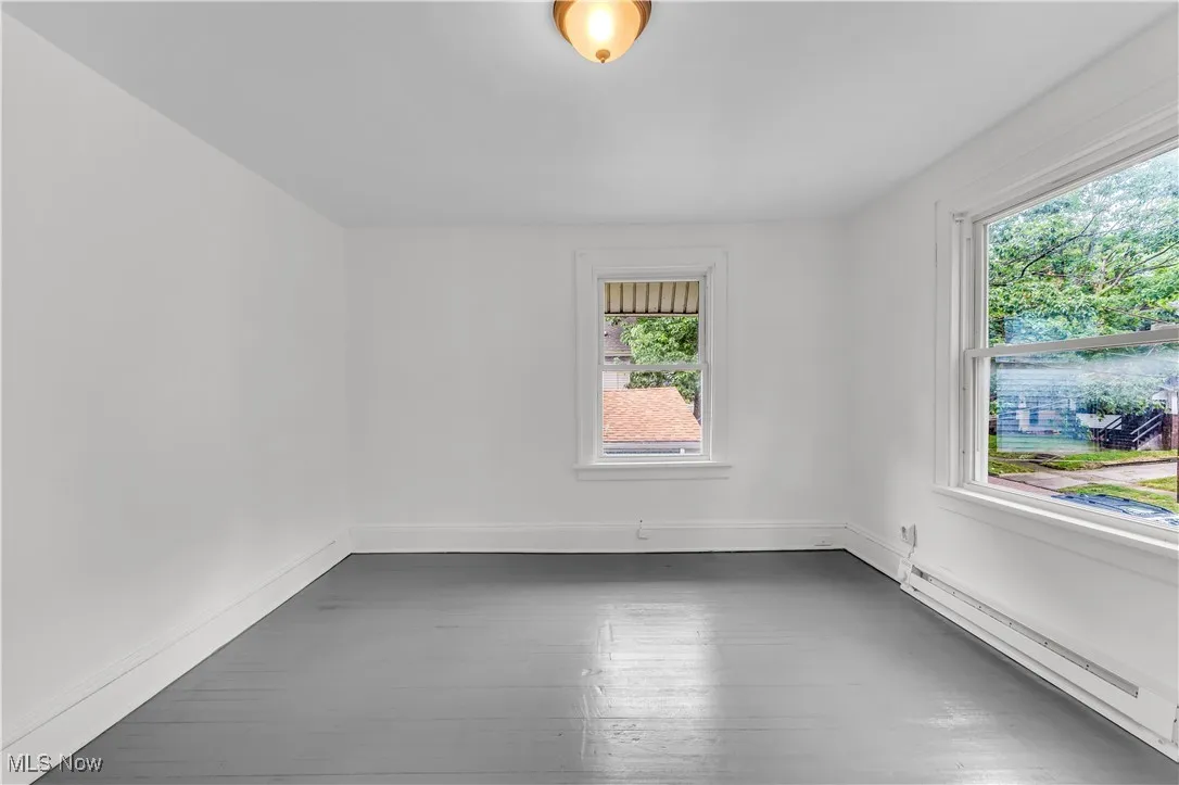 Spare room featuring baseboard heating and dark wood finished floors