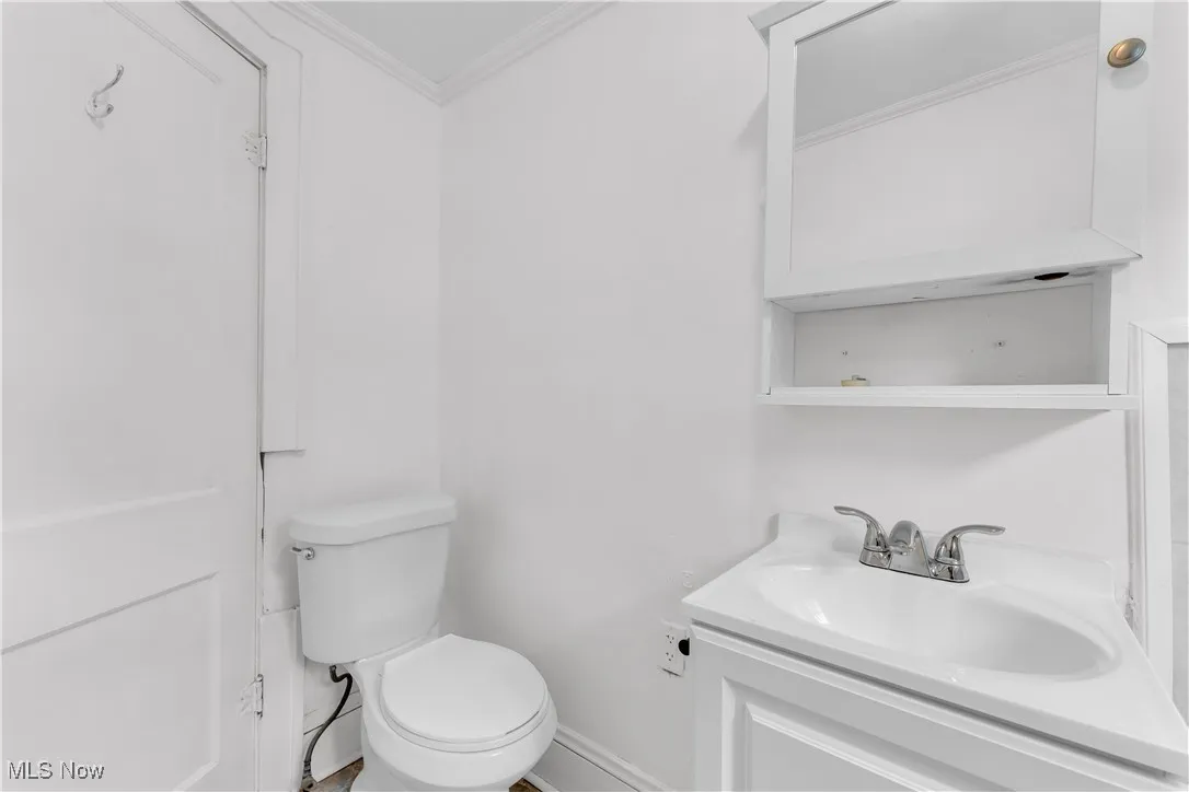 Half bath featuring ornamental molding and vanity
