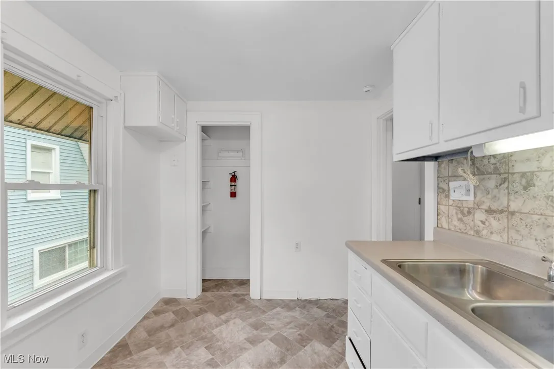 Kitchen with light countertops, stone finish flooring, tasteful backsplash, and white cabinetry