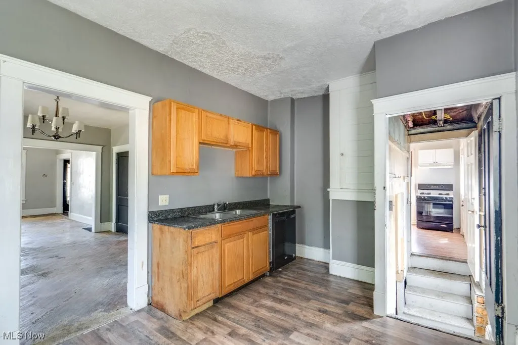 Kitchen with a chandelier, a textured ceiling, white gas range, dark wood-style floors, and black dishwasher