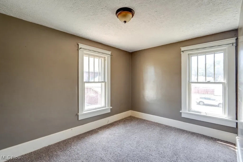 Unfurnished room featuring a textured ceiling and carpet flooring