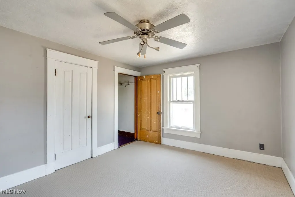 Unfurnished bedroom featuring light colored carpet, a textured ceiling, and ceiling fan