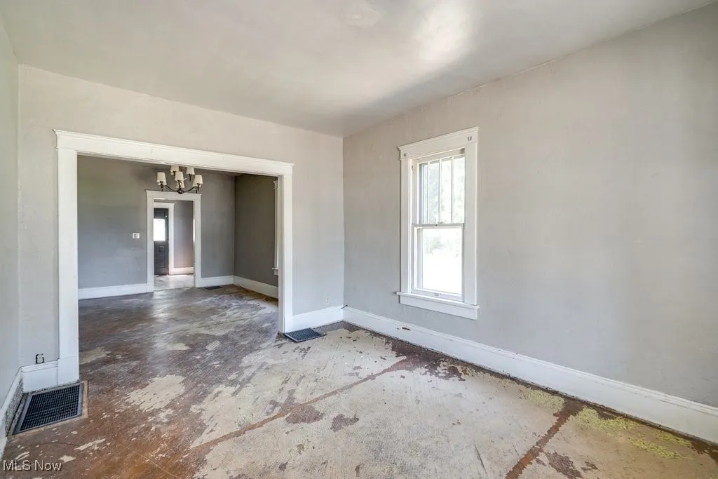 Empty room with a chandelier and baseboards