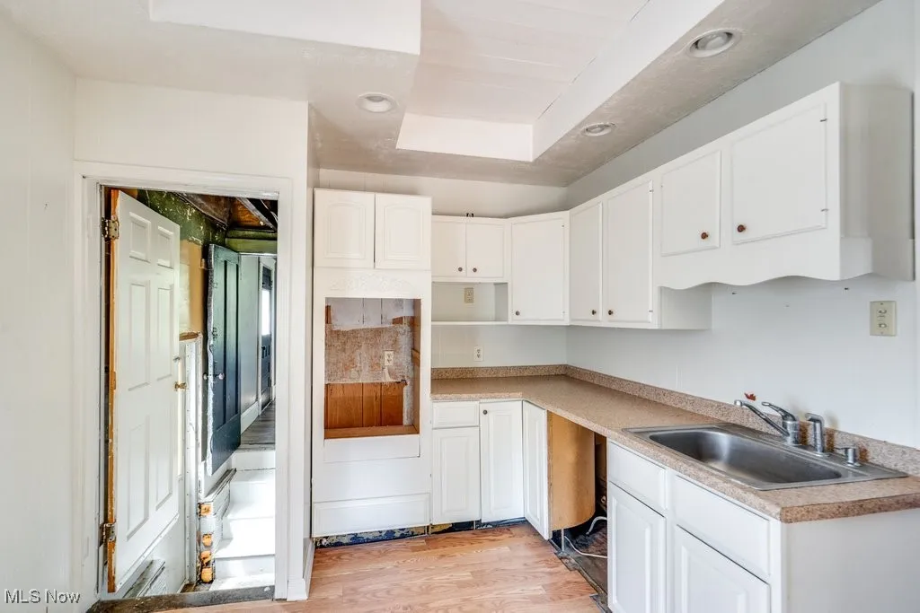 Kitchen with light wood finished floors, white cabinetry, recessed lighting, and light countertops