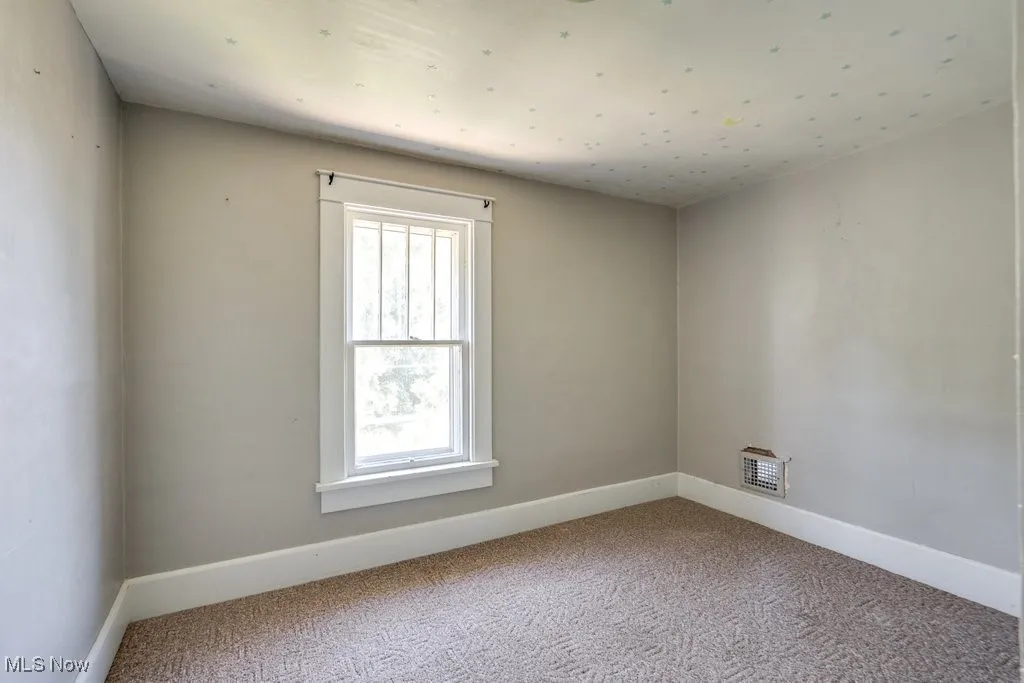 Carpeted empty room with baseboards