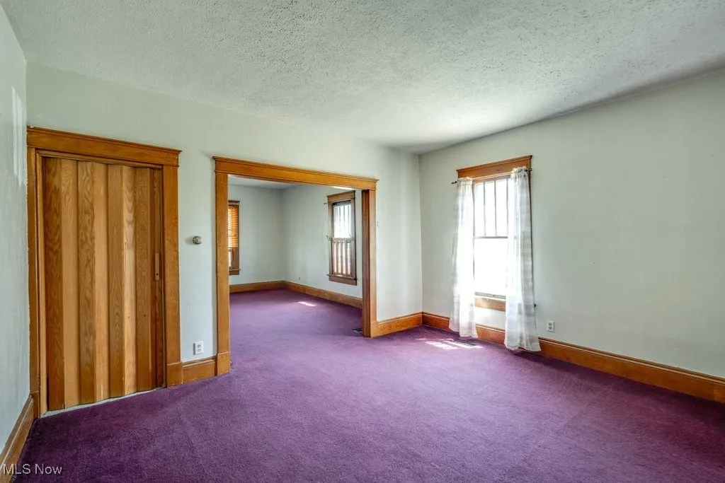 Carpeted empty room with a textured ceiling and baseboards