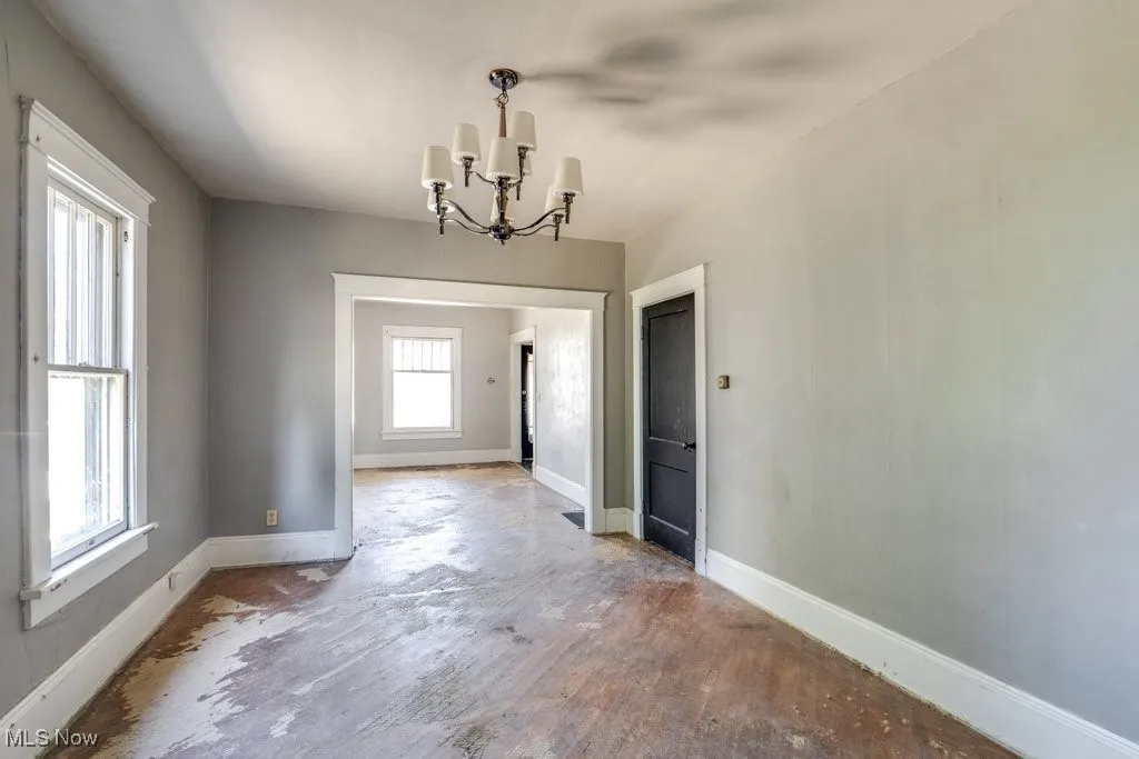 Unfurnished dining area featuring a chandelier and baseboards