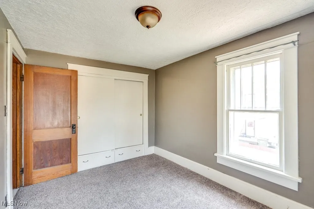 Unfurnished bedroom featuring a textured ceiling, carpet, and a closet