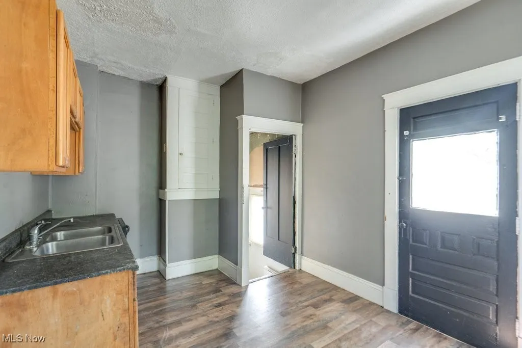 Kitchen featuring dark wood finished floors, dark countertops, a textured ceiling, and brown cabinets