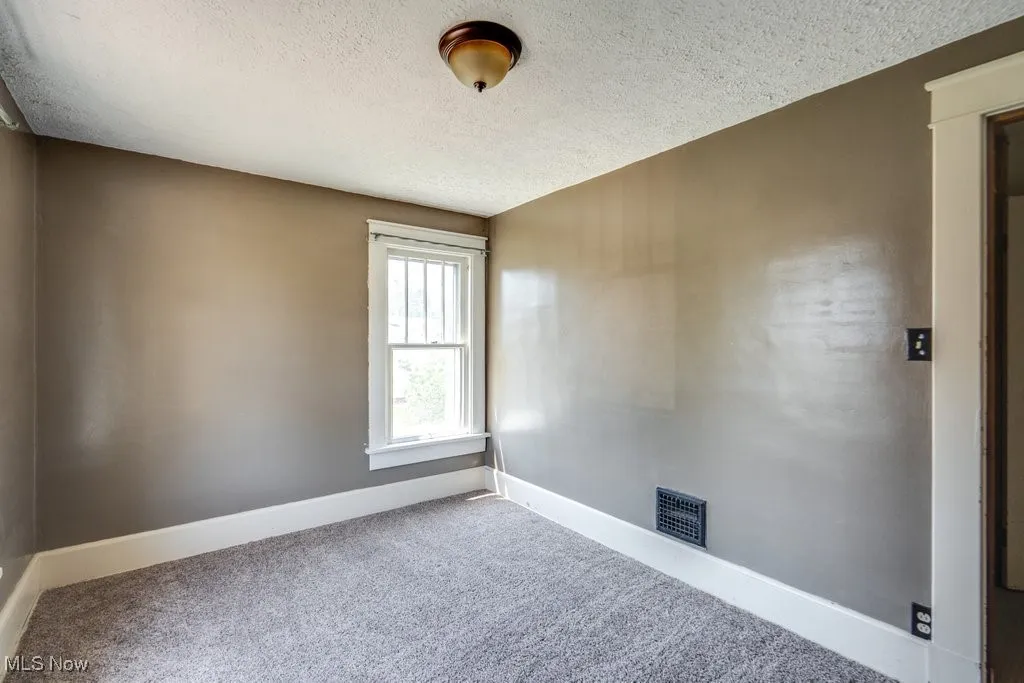 Empty room featuring carpet flooring and a textured ceiling