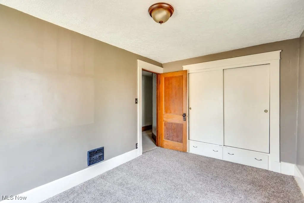 Unfurnished bedroom with carpet floors, a textured ceiling, and a closet