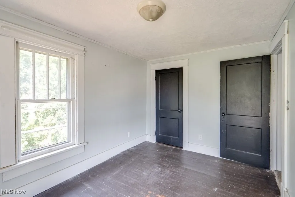 Unfurnished bedroom featuring wood finished floors, crown molding, and a textured ceiling