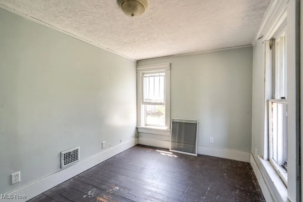 Unfurnished room with hardwood / wood-style floors, crown molding, and a textured ceiling